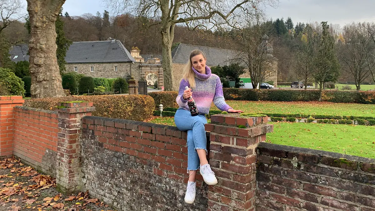 Daria Bücheler sitzt auf der Mauer vor dem Serien-Schloss "Königsbrunn".