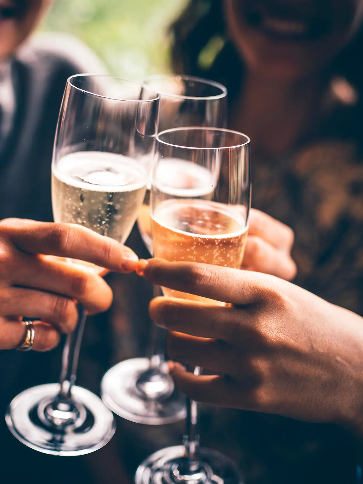 Three female friends celebrating with champagne. They are sitting in a bar and toasting with glasses of champagne.