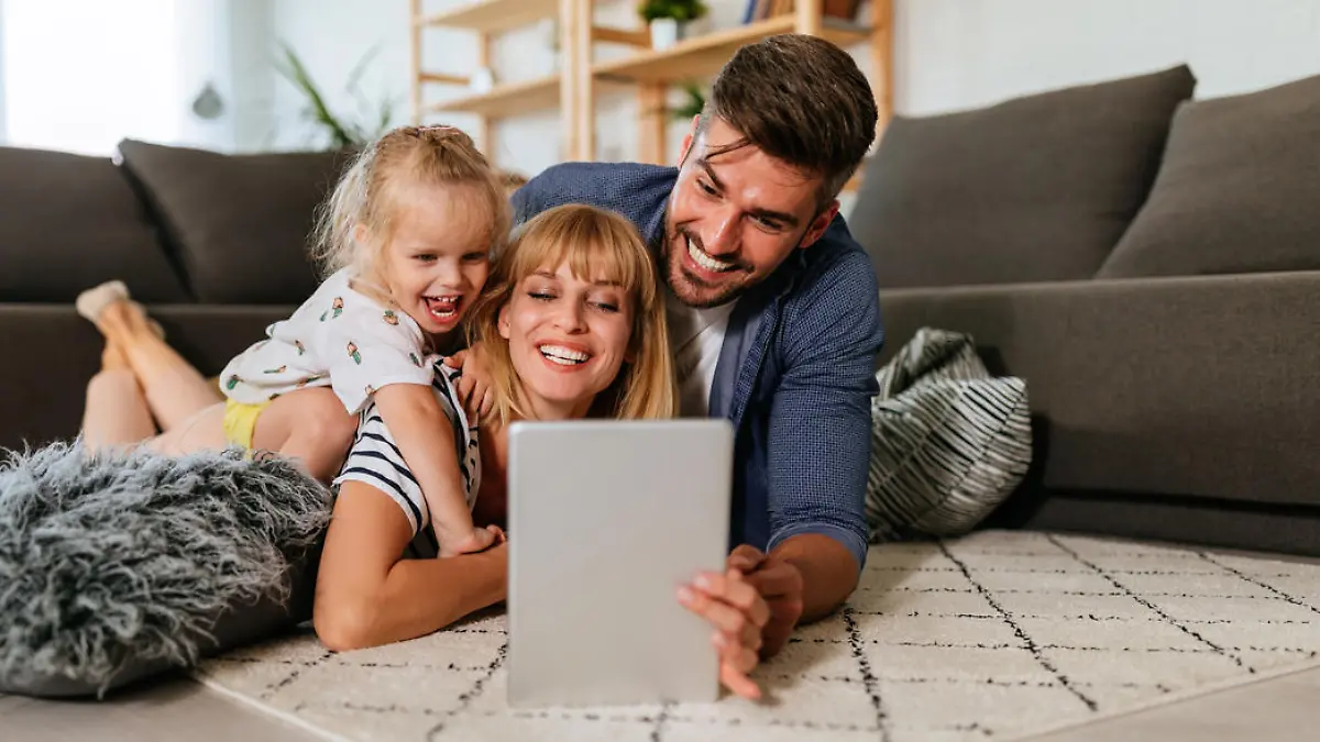 Eltern und kleine Tochter schauen gut gelaunt auf ein Tablet