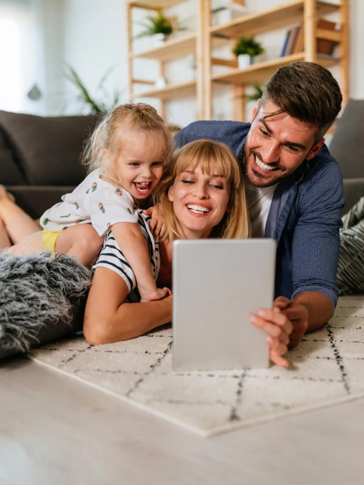Eltern und kleine Tochter schauen gut gelaunt auf ein Tablet