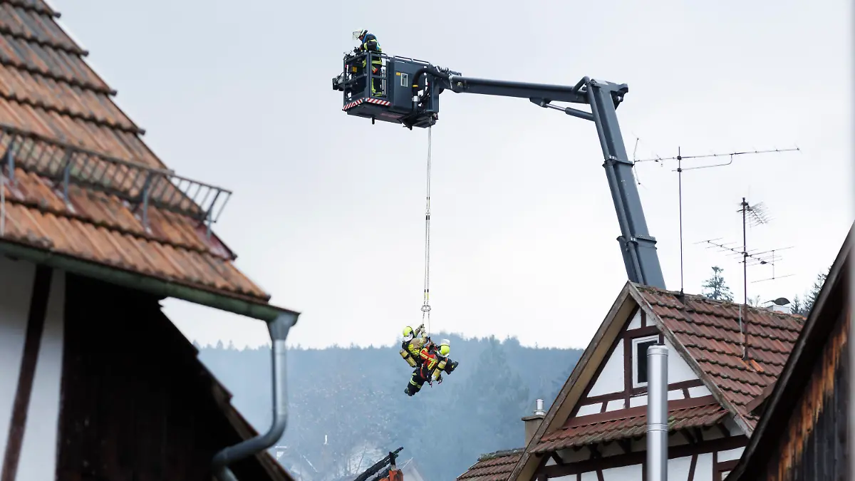 dpatopbilder - 13.04.2023, Baden-Württemberg, Gernsbach: Mit einem Spezialfahrzeug werden Feuerwehrleute von oben in das abgebrannte Haus abgelassen. Am frühen Morgen ist eine zum Wohnhaus umgebaute ehemalige Gaststätte in Gernsbach in Brand geraten. Einige Bewohner konnten gerettet werde, während mehrere Personen am Vormittag noch als vermisst gelten. Foto: Julian Rettig/dpa +++ dpa-Bildfunk +++