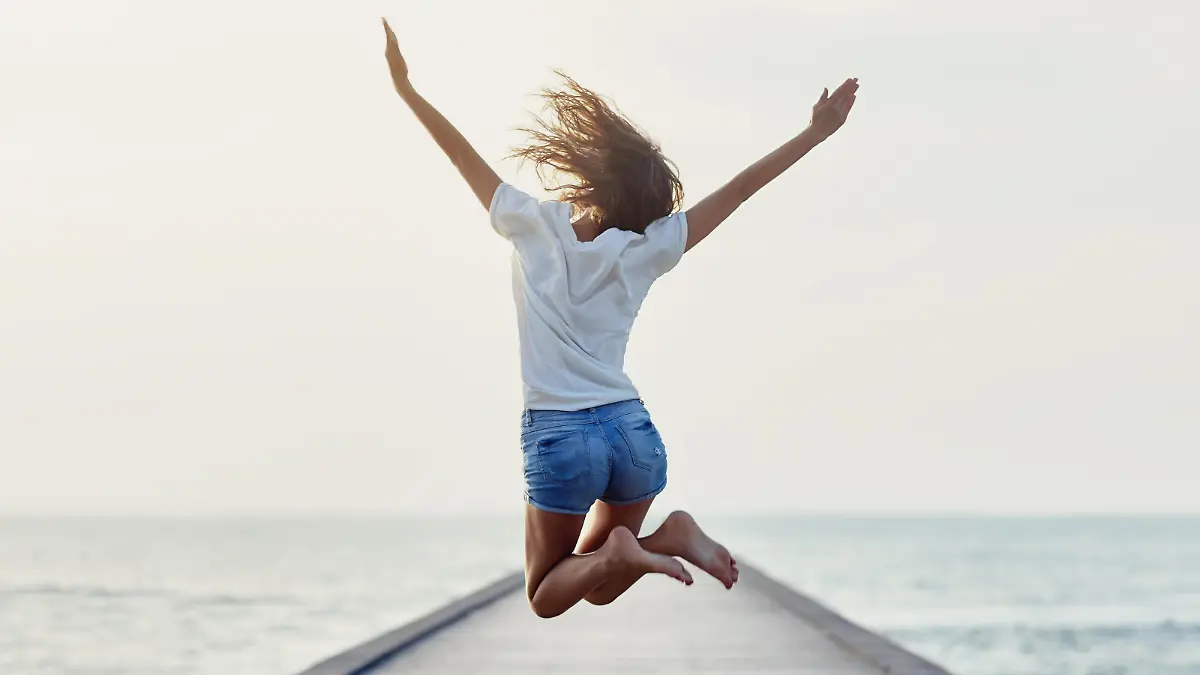 Back view of jumping girl on the pier. Freedom concept