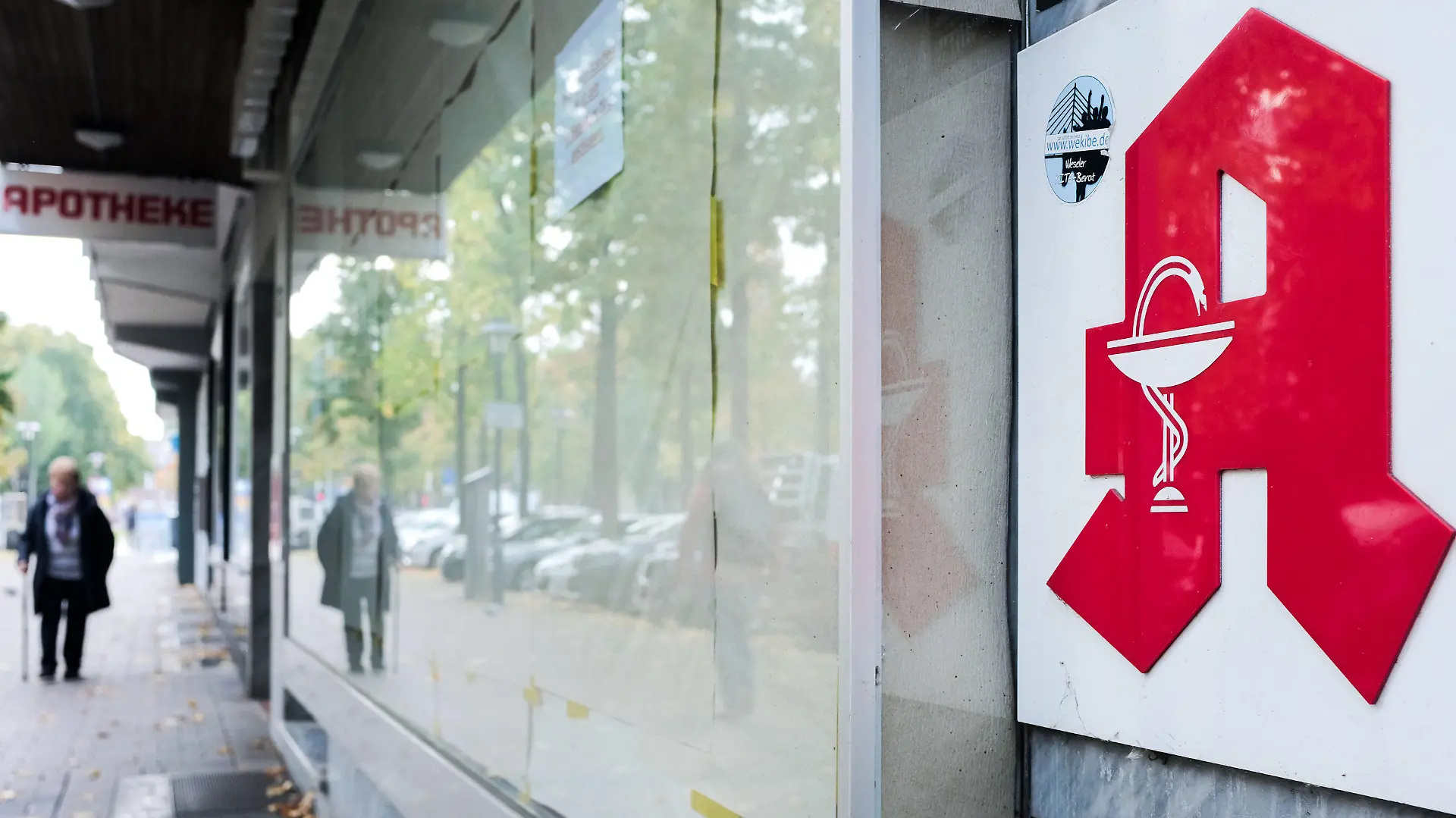 ARCHIV - 23.10.2019, Nordrhein-Westfalen, Wesel: Eine Frau geht an einer geschlossenen Apotheke vorbei. Die Schaufenster der ehemaligen Apotheke sind verhängt. Die Zahl der Apotheken in Westfalen-Lippe ist auch 2019 deutlich gesunken. Im vergangenen Jahr hätten 65 Schließungen nur elf Neueröffnungen gegenübergestanden, teilte die Apothekerkammer Westfalen-Lippe am Mittwoch in Münster mit. Foto: Martin Gerten/dpa +++ dpa-Bildfunk +++