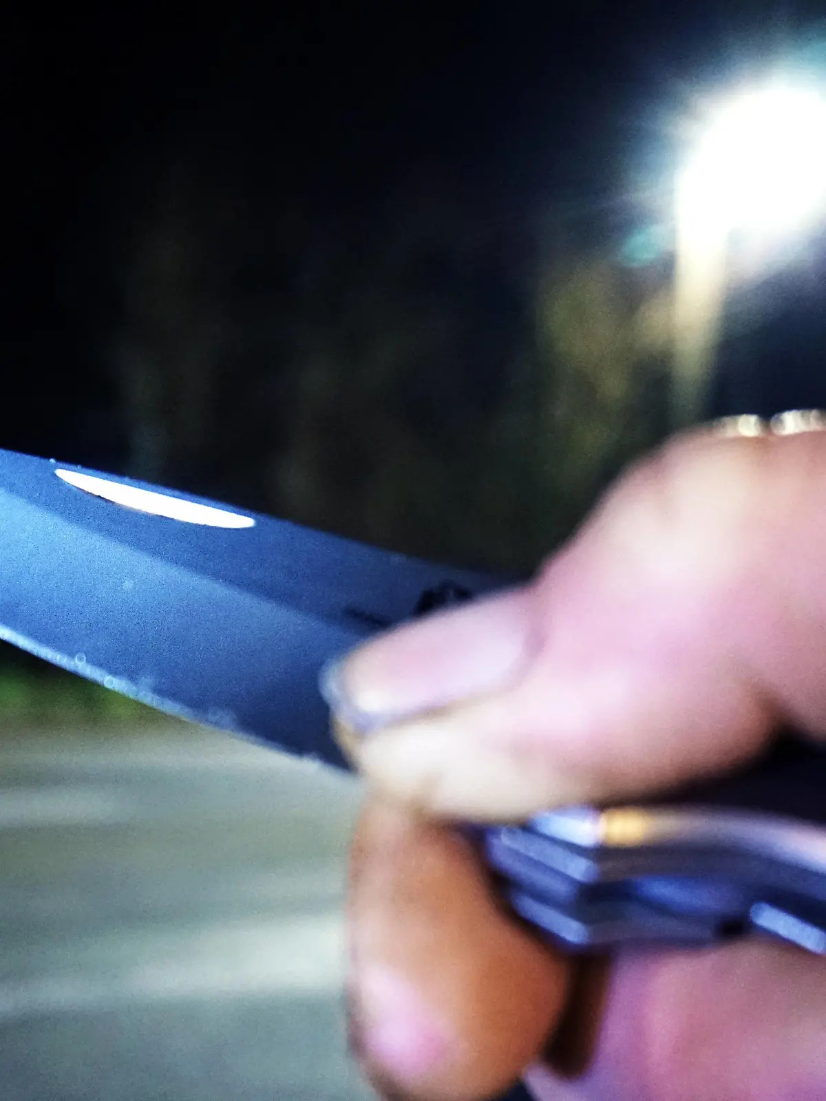 Kriminalität, Raub und Überfall / Raubüberfall - Symbolbilder Angriff mit Messer / Messerangriff - Symbolbilder .Messer als Kampfmittel und Waffe Eine Person hält bei Dunkelheit an einer Straße ein Messer in der Hand. *** Knife as a combat device and weapon A person holds a knife in his hand in the dark on a street