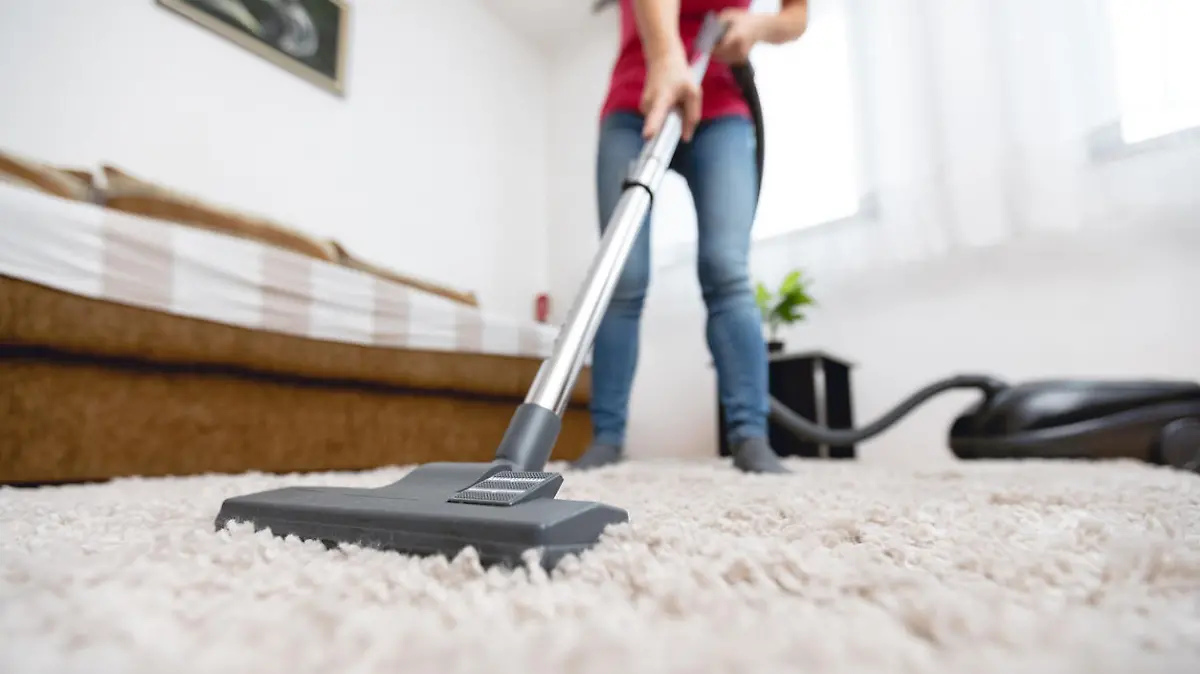 Frau staubsaugt ihren Teppich