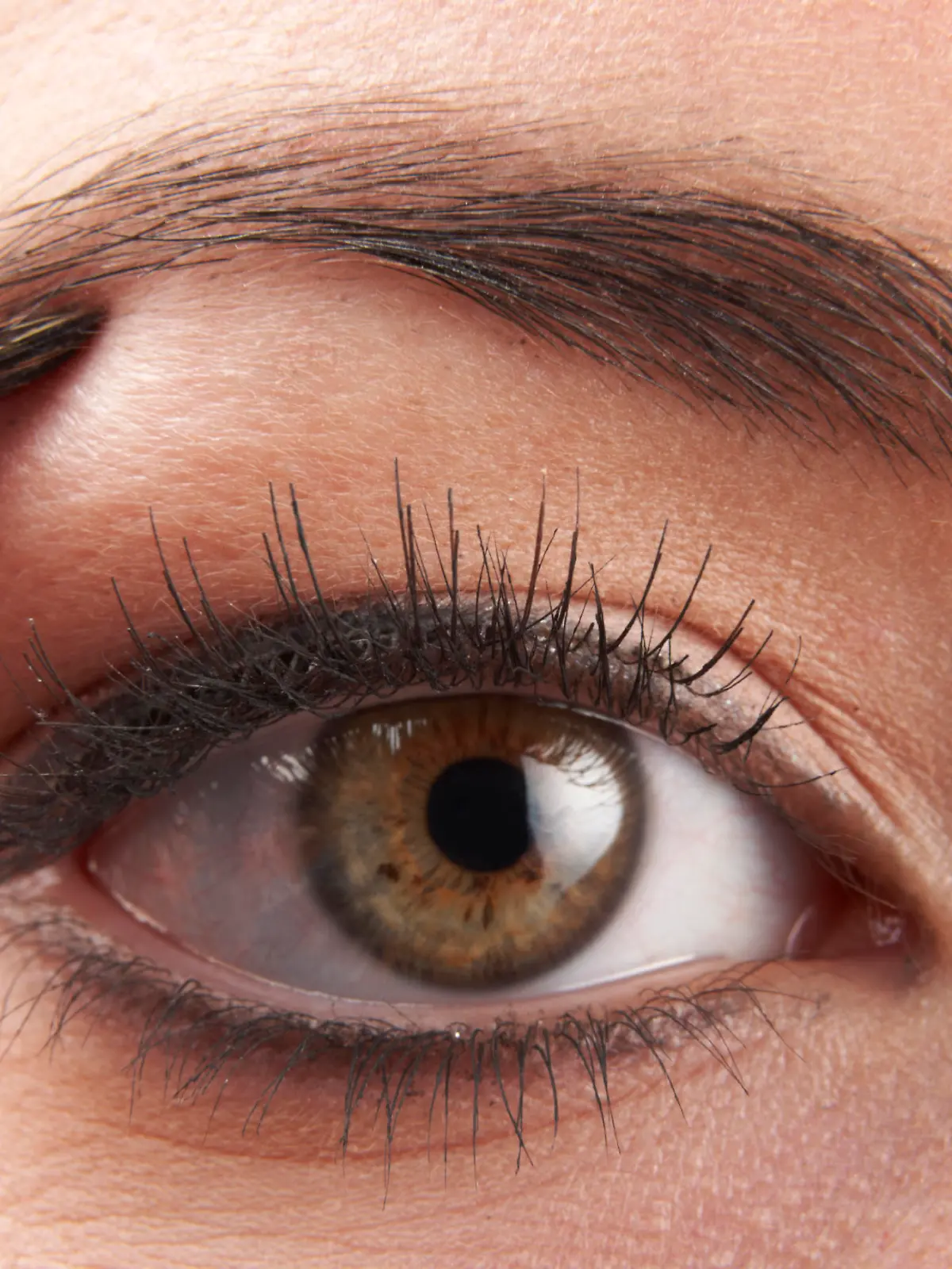woman applying eye make-up with brush on white background