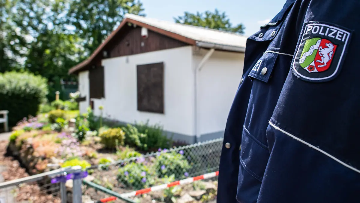 ARCHIV - 06.06.2020, Nordrhein-Westfalen, Münster: Bei den Ermittlungen nach schwerem sexuellem Missbrauch von Kindern steht ein Polizeibeamter vor der Gartenlaube, wo der vermutliche Haupttäter Teile seiner Server-Anlage unterbrachte. Im Fall des schweren sexuellen Missbrauchs von Kindern in Münster beginnt am 12. November 2020 der Prozess gegen fünf Angeklagte. Das teilte das Landgericht Münster am 19.10.2020 mit. Foto: Guido Kirchner/dpa +++ dpa-Bildfunk +++