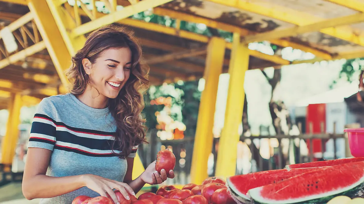 Smiling woman choosing fruits and vegetables on the farmer's market.