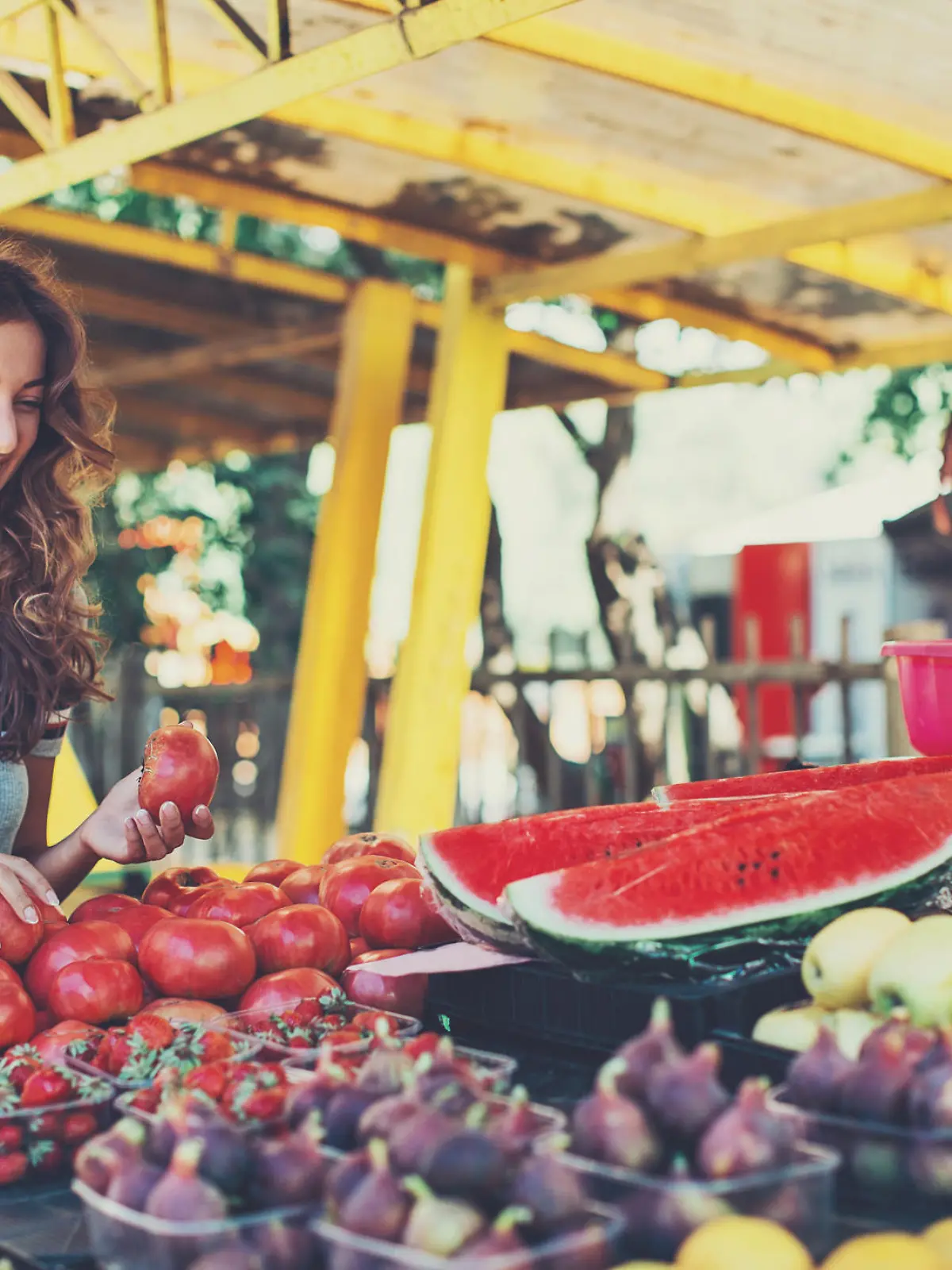 Smiling woman choosing fruits and vegetables on the farmer's market.