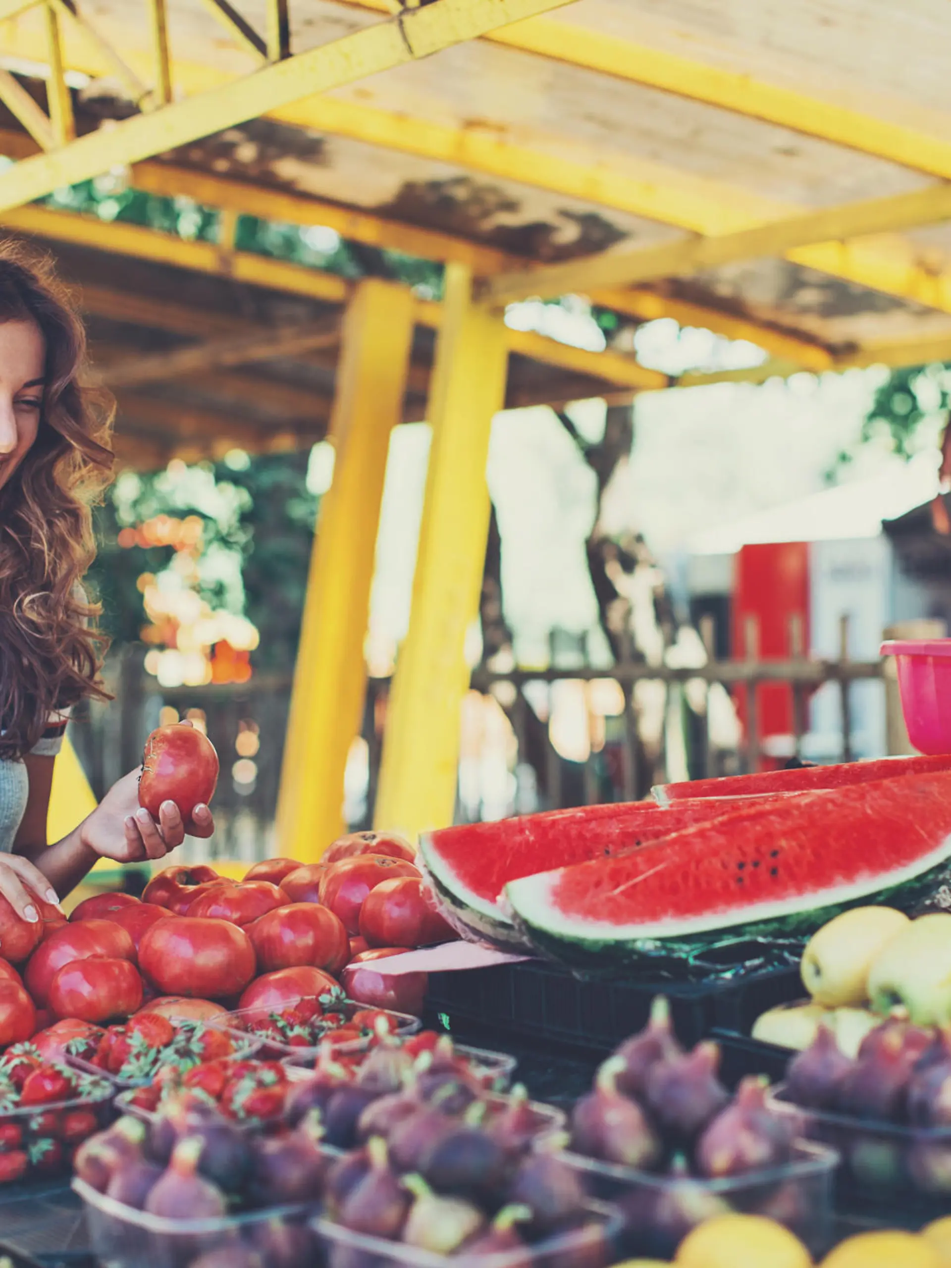 Smiling woman choosing fruits and vegetables on the farmer's market.