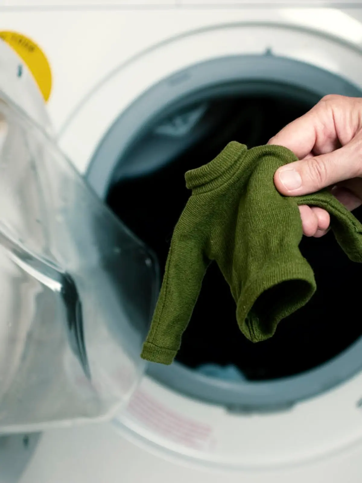 Mann holt eingelaufenen Mini-Wollpulli aus Waschmaschine