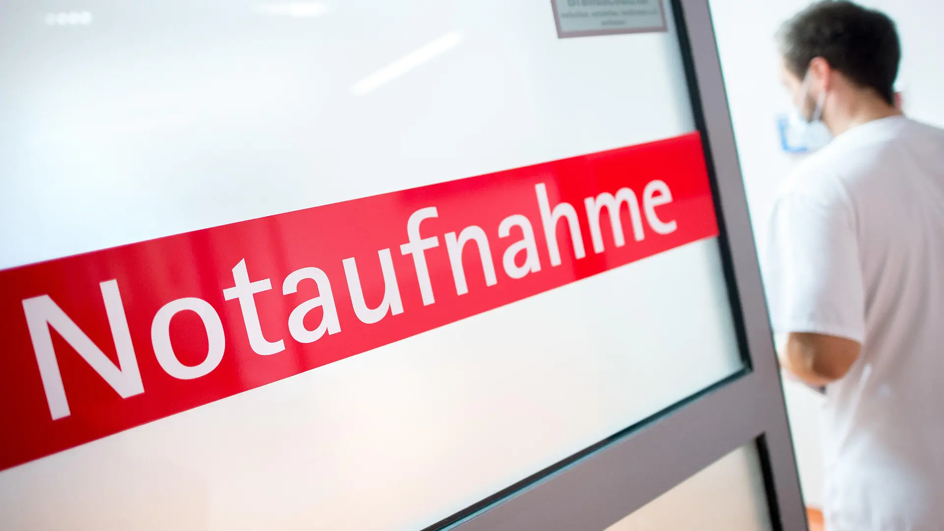 ARCHIV - 27.03.2018, Niedersachsen, Braunschweig: Ein Krankenpfleger steht in einem Krankenhaus neben einer Glastür mit der Aufschrift «Notaufnahme». (zu dpa "Stiftung Patientenschutz ist gegen Strafgebühr bei Notaufnahme-Besuch") Foto: Hauke-Christian Dittrich/dpa +++ dpa-Bildfunk +++