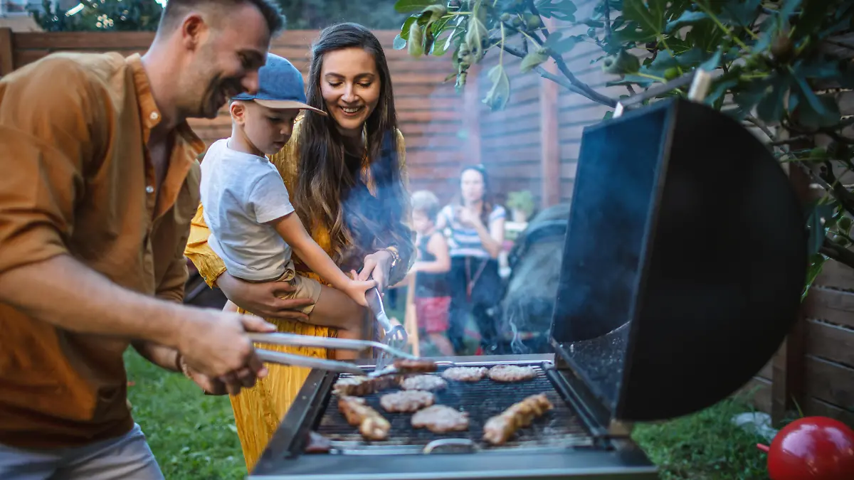 Photo of young happy family having a barbecue party in backyard