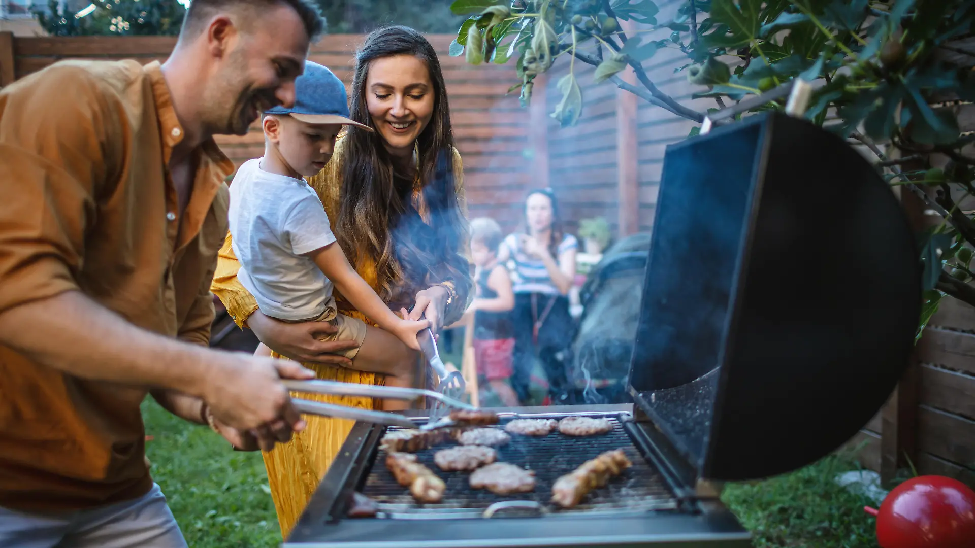 Photo of young happy family having a barbecue party in backyard