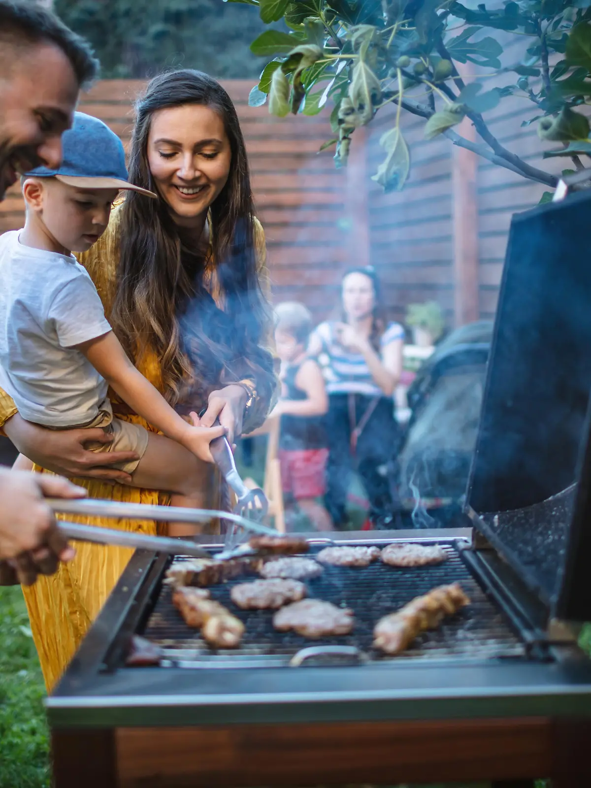 Photo of young happy family having a barbecue party in backyard