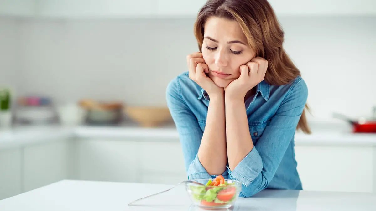 Frau schaut skeptisch auf kleine Schüssel Salat