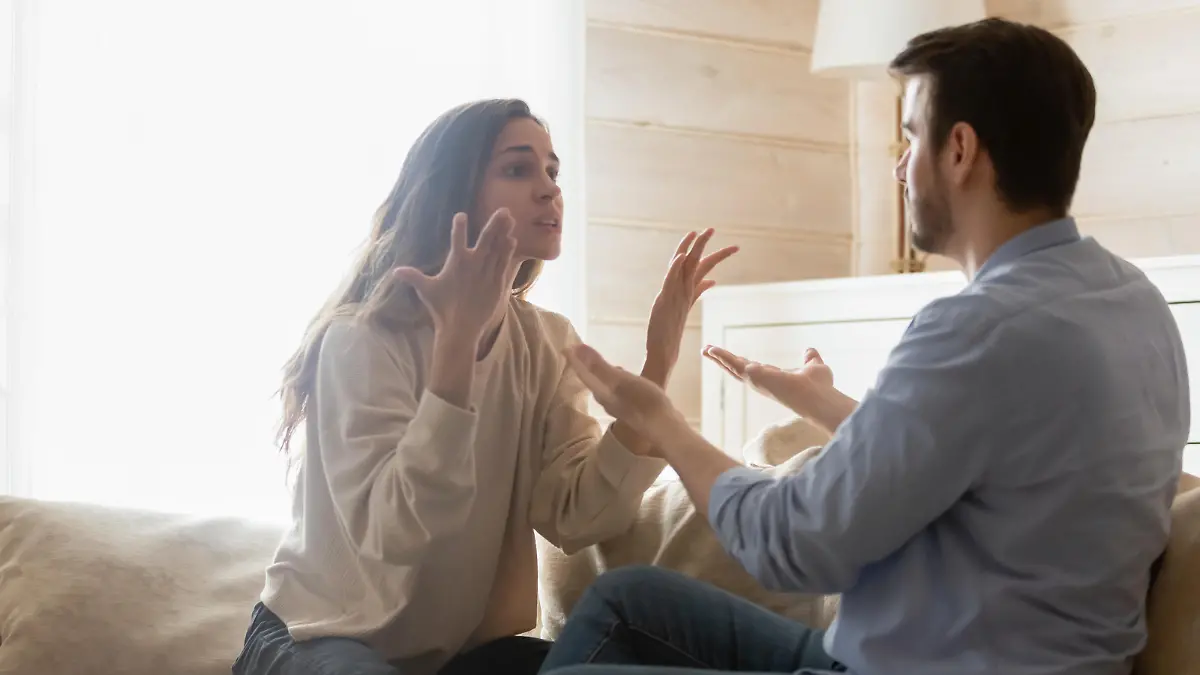 Angry young couple sit on couch in living room having family fight or quarrel suffer from misunderstanding, millennial husband and wife dispute involved in argument, relationships problems concept