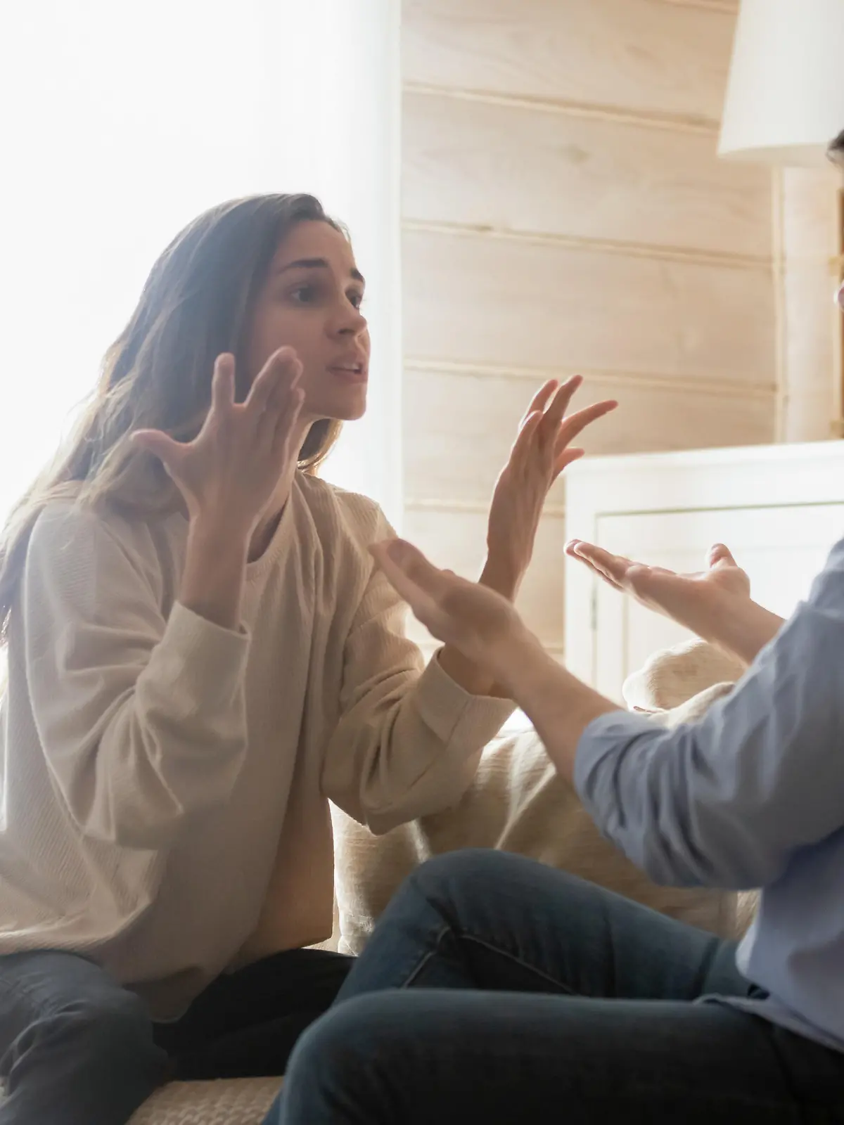 Angry young couple sit on couch in living room having family fight or quarrel suffer from misunderstanding, millennial husband and wife dispute involved in argument, relationships problems concept