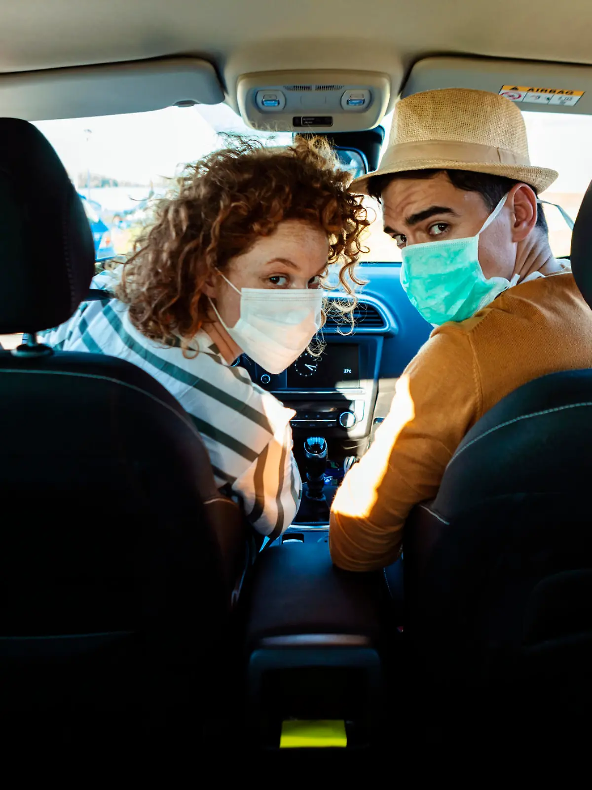 Mann und Frau mit Corona-Maske im Auto