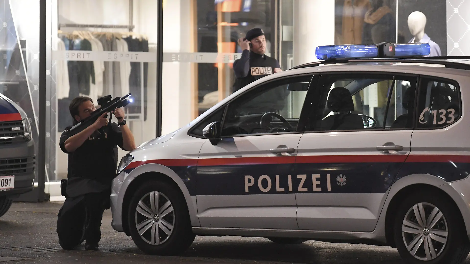 02.11.2020, Österreich, Wien: Ein Polizist hat sein Gewehr im Anschlag und geht hinter einem Polizeiauto in Deckung. Bei den Schüssen in Wien handelt es sich nach den Worten von Österreichs Innenminister augenscheinlich um einen Terroranschlag. Foto: Roland Schlager/APA/dpa +++ dpa-Bildfunk +++