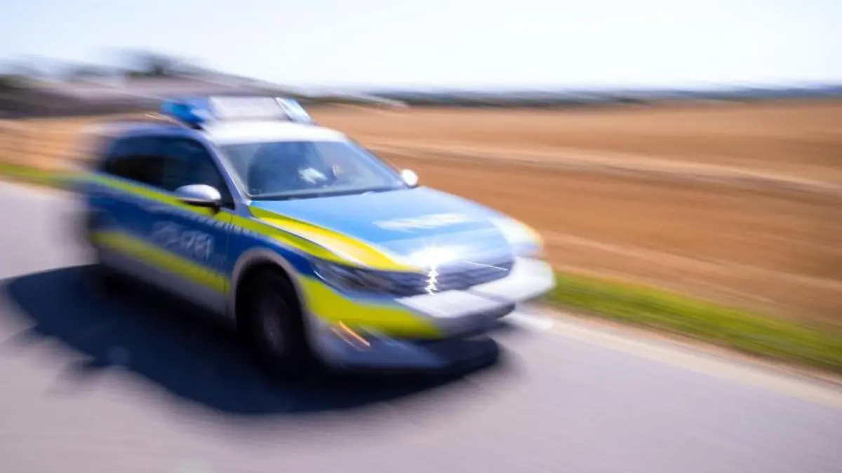 Ein Polizeiauto fährt über eine Dorfstraße