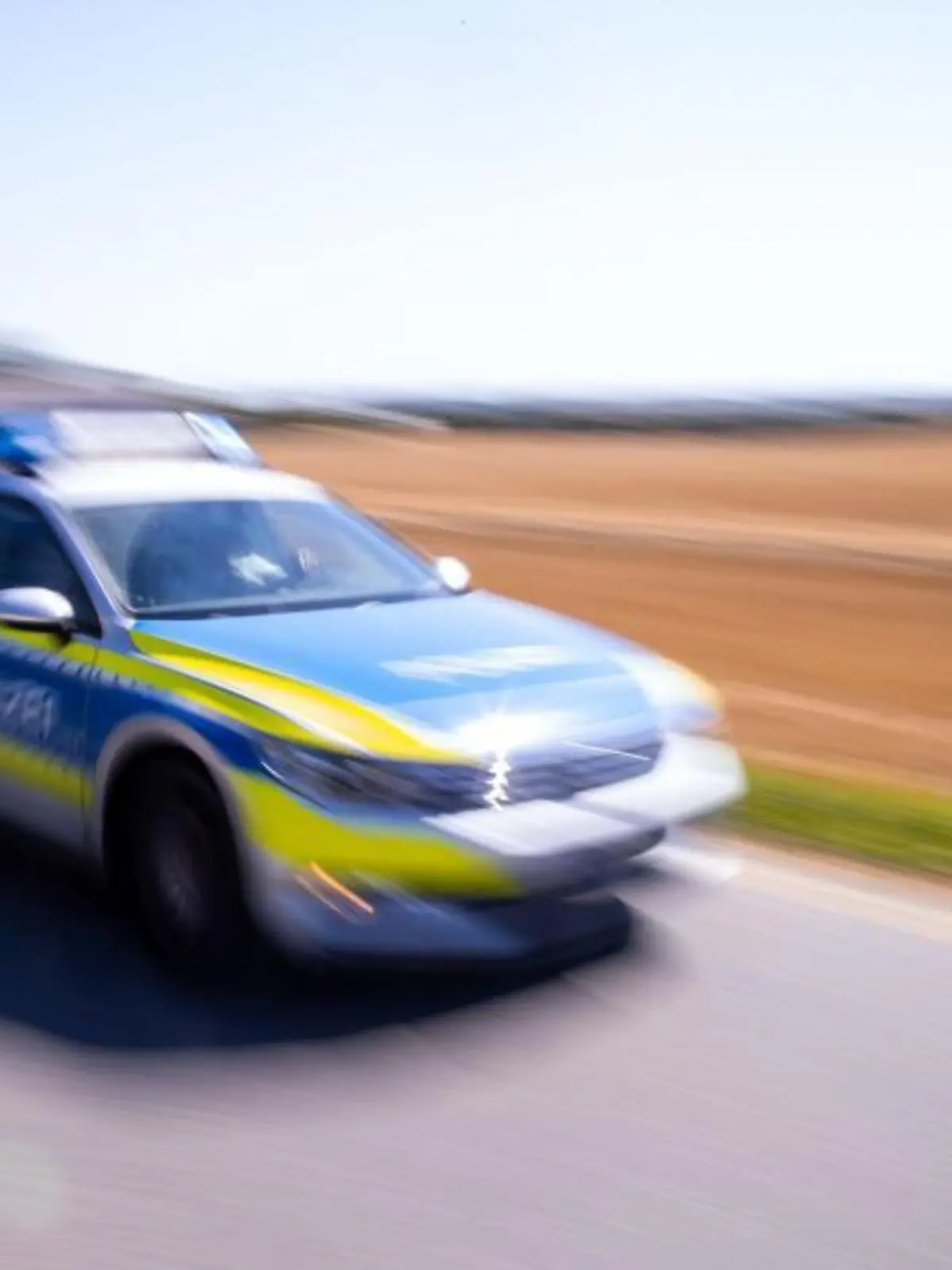 Ein Polizeiauto fährt über eine Dorfstraße
