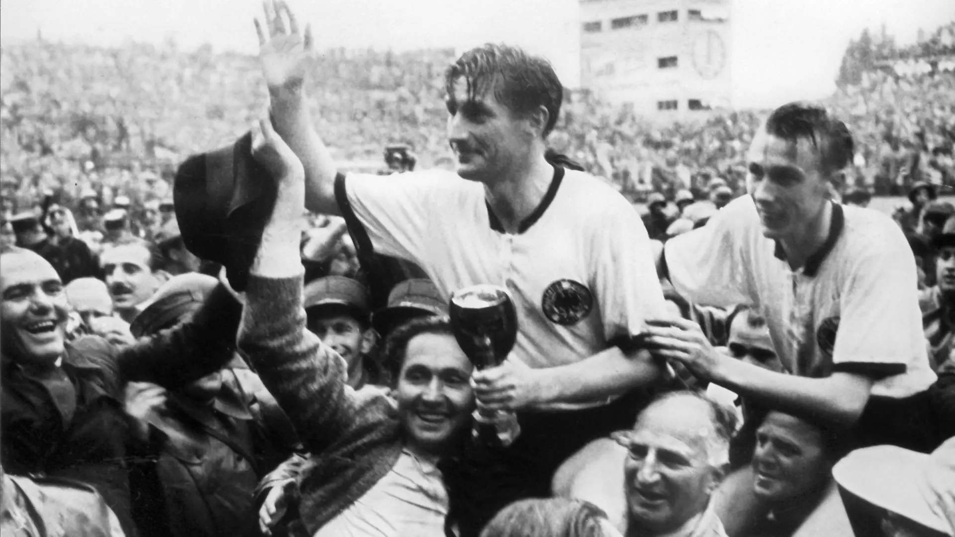 ARCHIV - 04.07.1954, Schweiz, Bern: Der deutsche Stürmer und Kapitän Fritz Walter (M, oben) und sein Lauterer Teamgefährte Horst Eckel (r) werden nach dem Triumph im Fußball-WM-Finale im Berner Wankdorfstadion von begeisterten Anhängern vom Spielfeld getragen. Fritz Walter hält den Jules-Rimet-Pokal in der Hand, den er mit seiner Mannschaft gewinnt. Am 31. Oktober wäre der im Jahr 2002 verstorbene Fritz Walter 100 Jahre alt geworden. Mit dem «Wunder von Bern» schrieb Fritz Walter Sportgeschichte. (zu dpa «Mehr als Fußball: Der Jahrhundertsportler Fritz Walter») Foto: picture alliance / dpa +++ dpa-Bildfunk +++