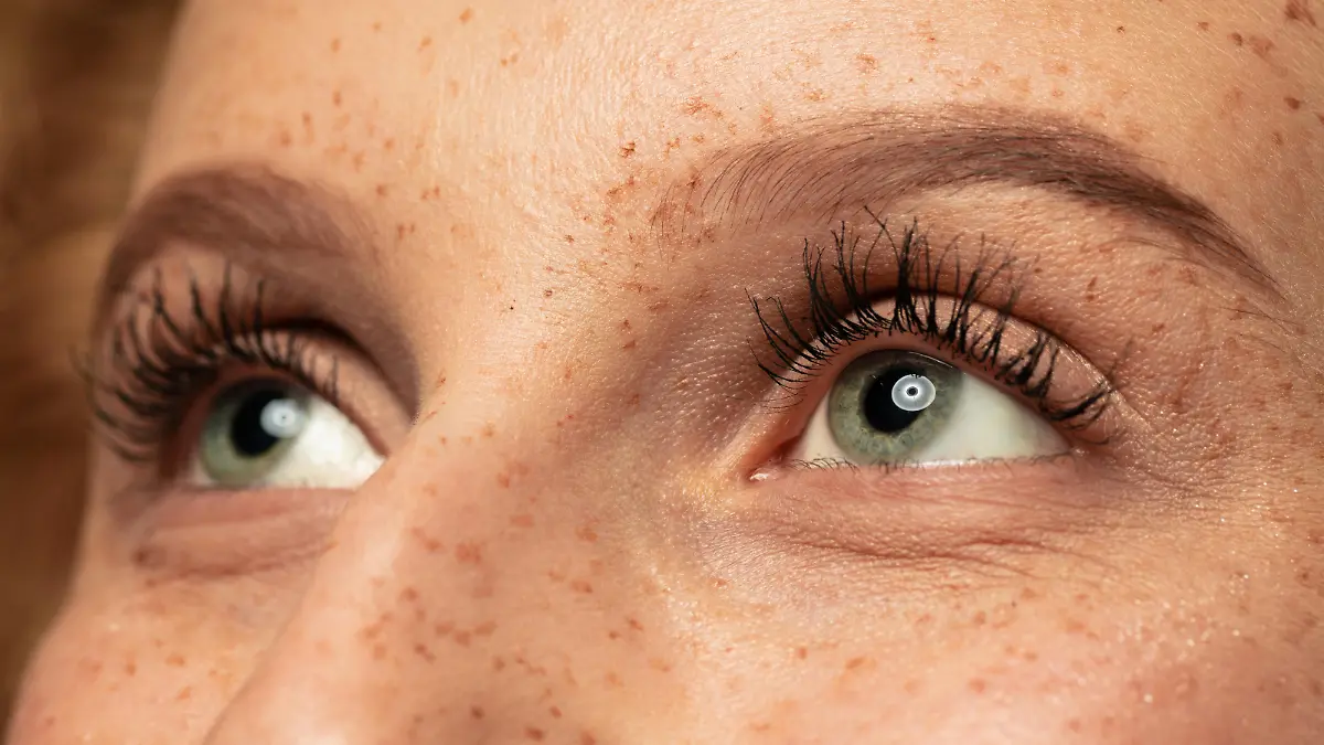 Frau im Close-up mit langen Wimpern guckt nach oben.