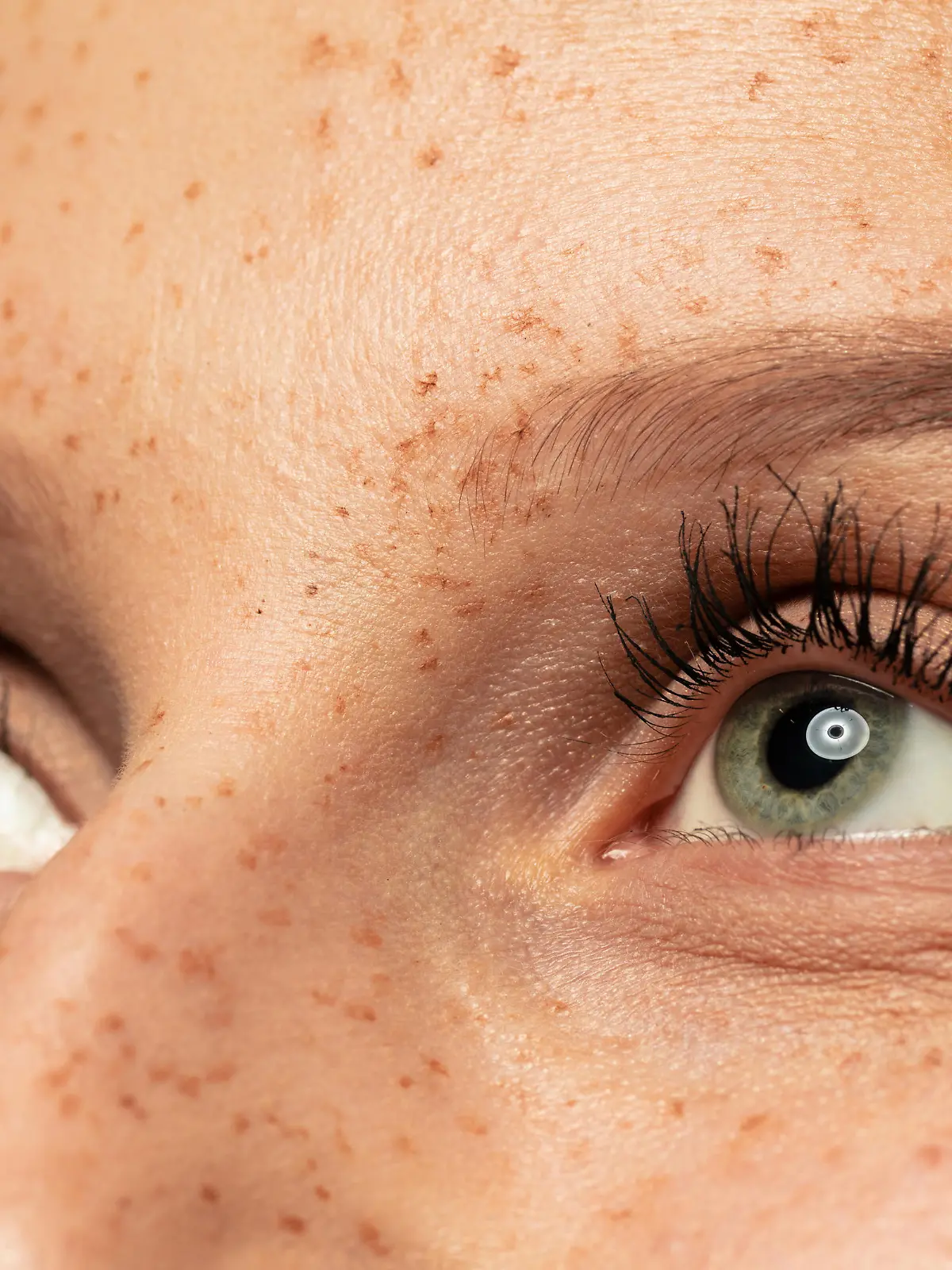 Frau im Close-up mit langen Wimpern guckt nach oben.