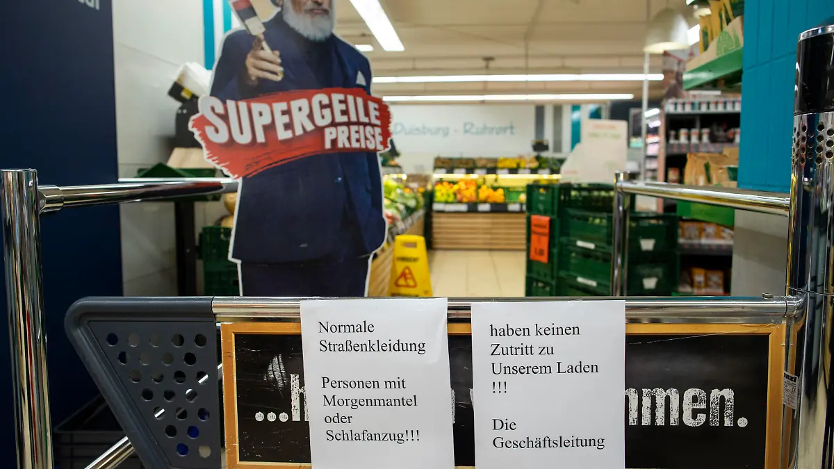 Auf einem Schild am Markteingang steht "Personen mit Morgenmantel oder Schlafanzug haben keinen Zutritt zu unserem Laden"