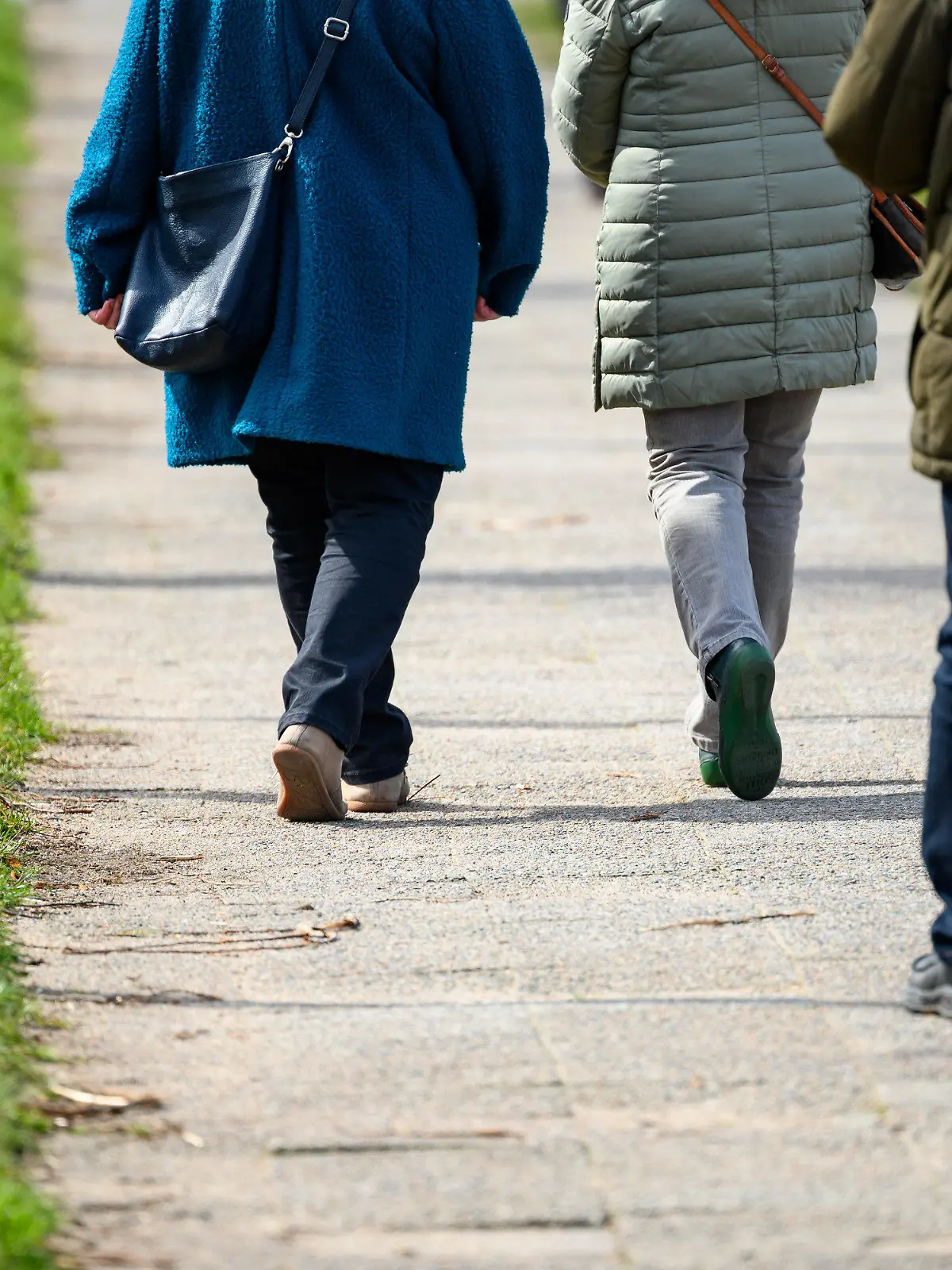 07.04.2023, Schleswig-Holstein, Lübeck: Spaziergänger laufen im Sonnenschein eine Allee entlang. Foto: Jonas Walzberg/dpa +++ dpa-Bildfunk +++