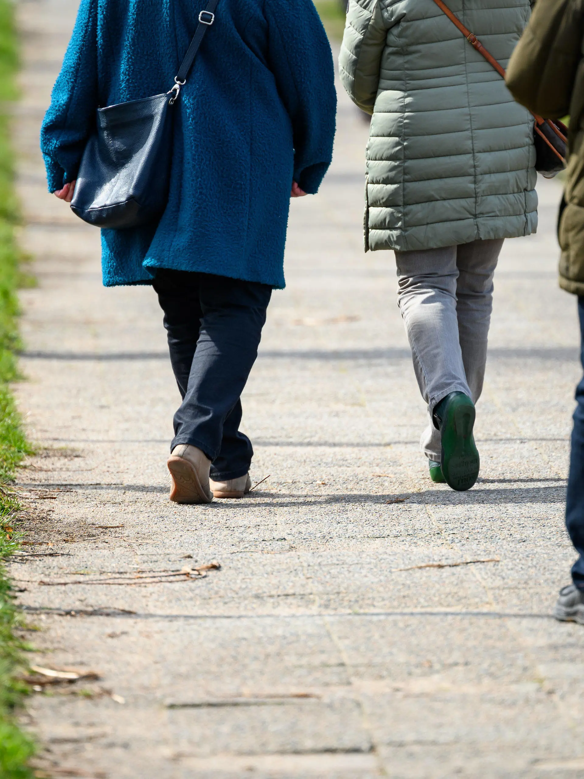 07.04.2023, Schleswig-Holstein, Lübeck: Spaziergänger laufen im Sonnenschein eine Allee entlang. Foto: Jonas Walzberg/dpa +++ dpa-Bildfunk +++