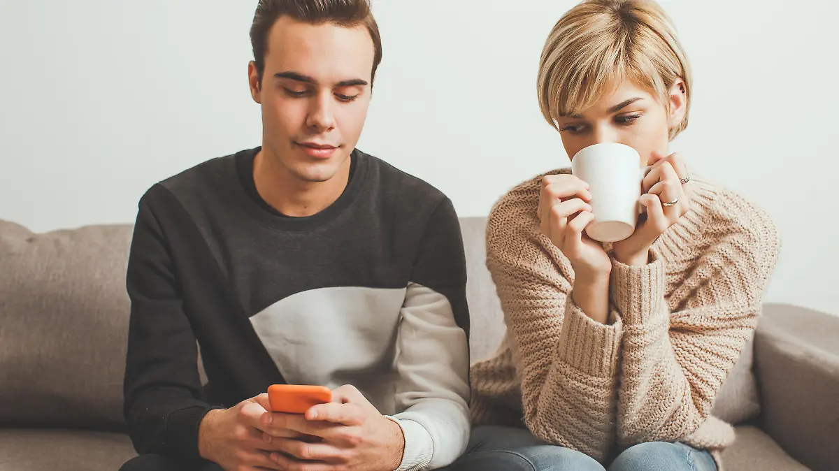 Frau schaut skeptisch auf Handy ihres Freundes