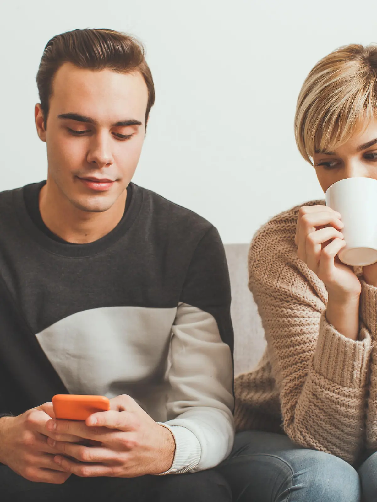 Frau schaut skeptisch auf Handy ihres Freundes