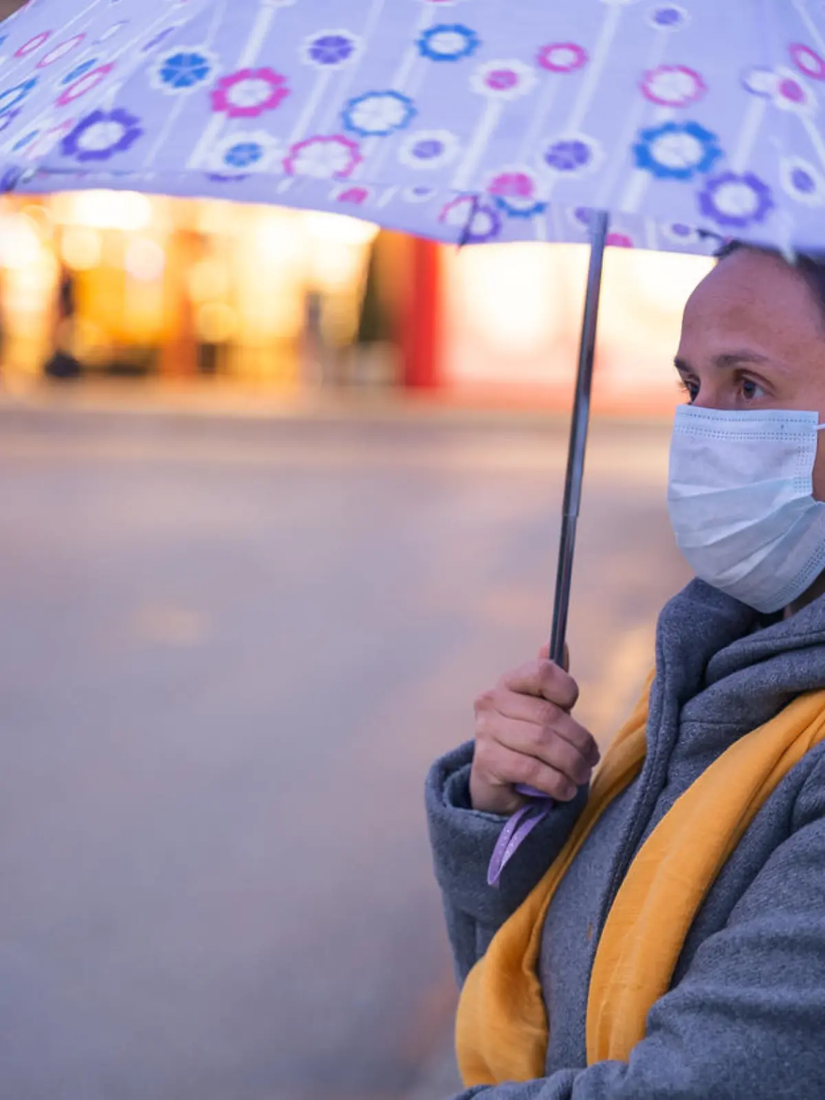 Frau mit Mund-Nasen-Maske und Regenschirm