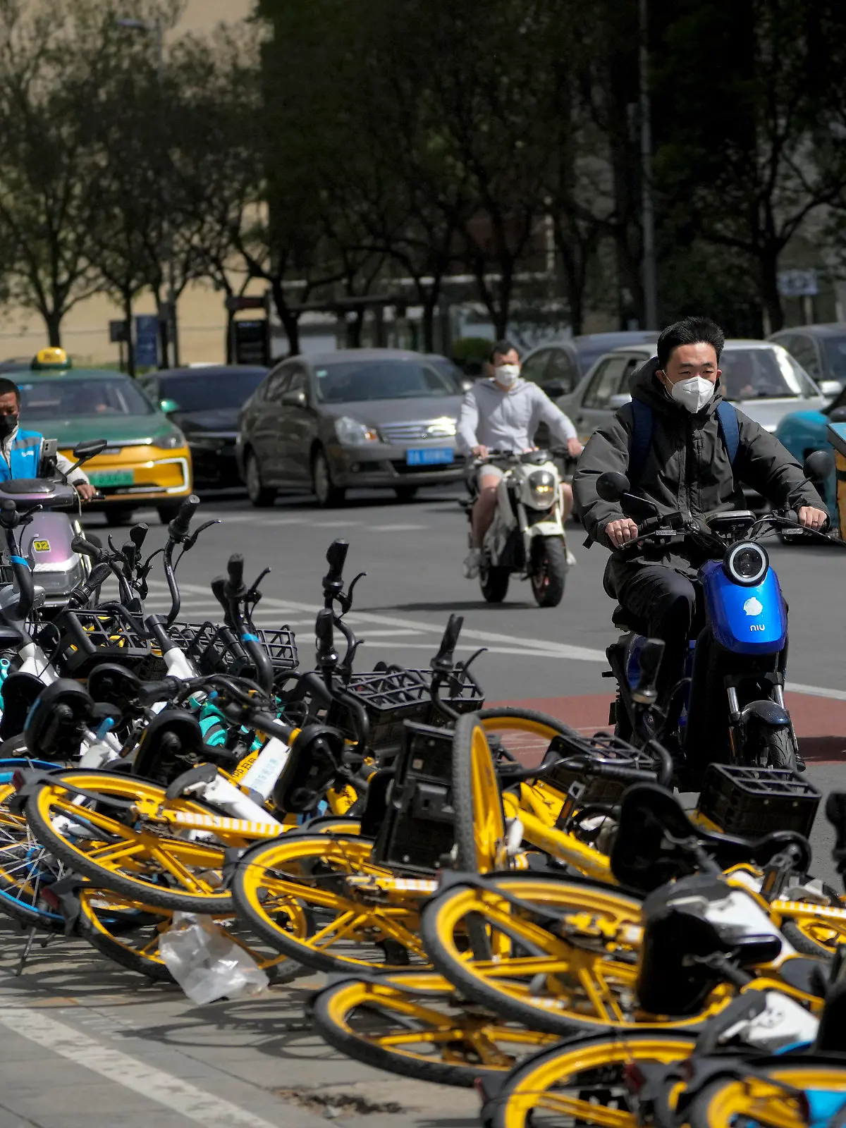 11.04.2023, China, Peking: Menschen fahren auf einer Straße an umgestürzten Fahrrädern vorbei, nachdem eine Böe eines Staub- und Sandsturms über Peking hinweggefegt ist. Ein schwerer Sandsturm ist über die chinesische Hauptstadt Peking und andere Regionen Nordchinas hinweggefegt. Der Index für die Luftverschmutzung in Peking stieg am Montagabend weit über die Skala-Obergrenze auf 1300, während Werte von 150 schon als «ungesund» gelten. Foto: Andy Wong/AP +++ dpa-Bildfunk +++