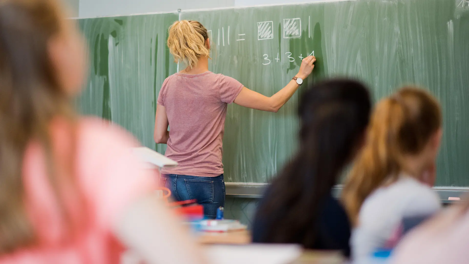 ARCHIV - 17.08.2016, Niedersachsen, Hannover: Eine junge Lehrerin schreibt an eine Schultafel im Mathematikunterricht einer 8. Klasse an einer Integrierten Gesamtschule. Nach den Sommerferien drohen an Niedersachsens Schulen erneut Engpässe bei der Lehrerversorgung. (zu dpa vom 08.07.2018) Foto: Julian Stratenschulte/dpa +++ dpa-Bildfunk +++
