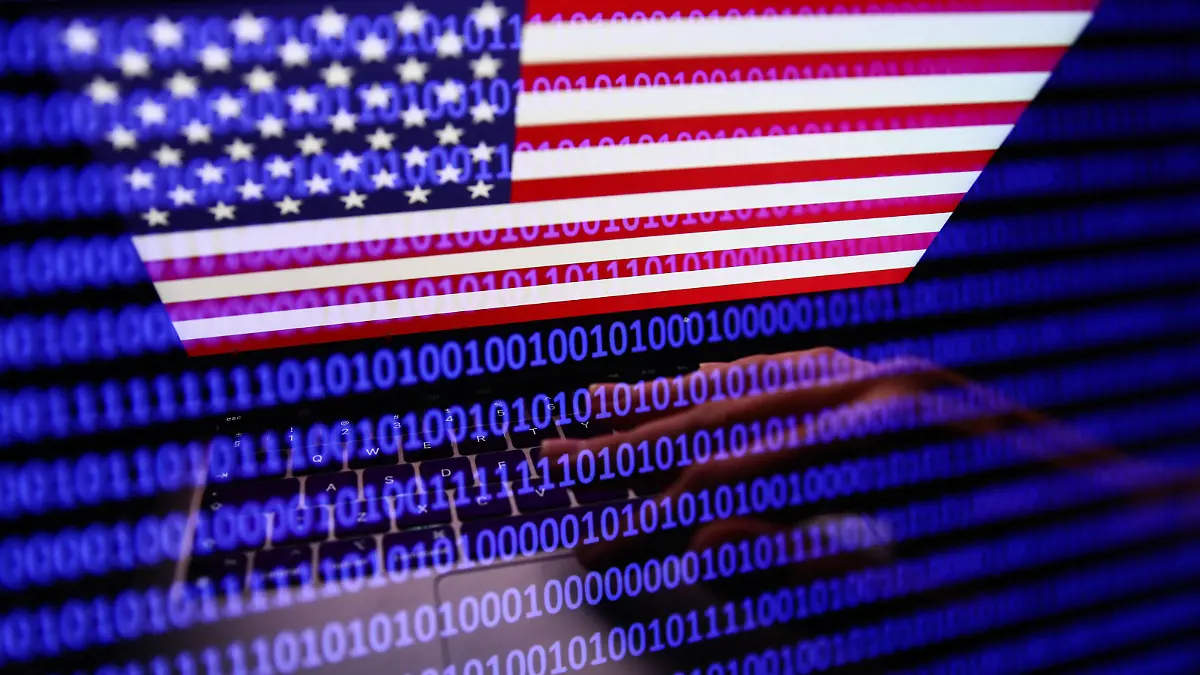 Flag of the United States displayed on a laptop screen and binary code displayed on a screen are seen in this multiple exposure illustration photo taken in Krakow, Poland on September 27, 2022. (Photo by Jakub Porzycki/NurPhoto)