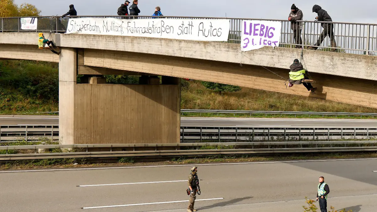 13.10.2020, Hessen, Idstein: Umweltaktivisten hängen an einer Brücke über der Autobahn 3 und protestieren gegen die Rodung von Bäumen im Herrenwald und Dannenröder Forst bei Stadtallendorf im Zusammenhang mit dem geplanten Ausbau der Autobahn 49. (zu dpa «Nach Blockade der A3: Unfall am Stauende») Foto: Jörg Halisch/dpa +++ dpa-Bildfunk +++