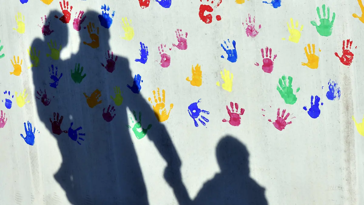 ARCHIV - ARCHIV - Der Schatten von einem Mann mit zwei Kindern zeichnet sich am 08.04.2015 an der Wand einer Kindertagesstätte ab, die mit bunten Handabdrücken verziert ist.(zu dpa «Studie: Armutsrisiko von Familien erhöht sich mit jedem Kind» vom 07.02.2018) Foto: Peter Kneffel/dpa +++ dpa-Bildfunk +++
