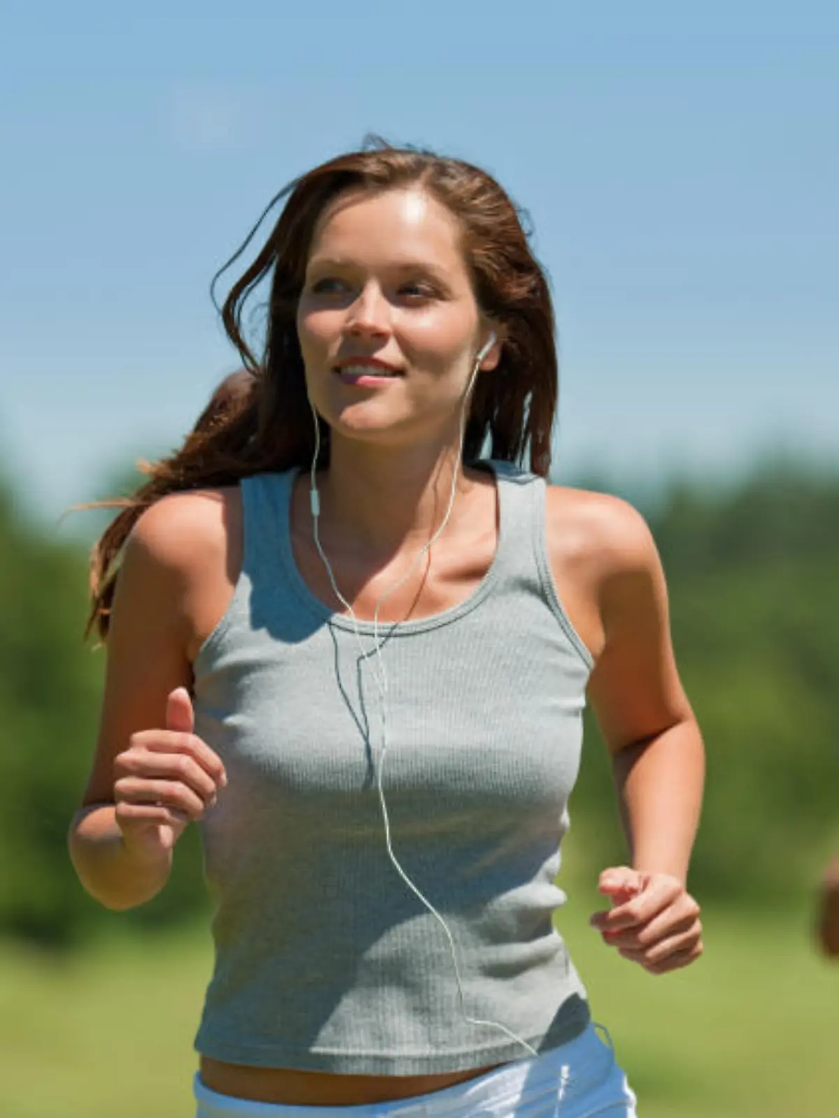 Brown hair woman with headphones jogging, man in background, shallow DOF