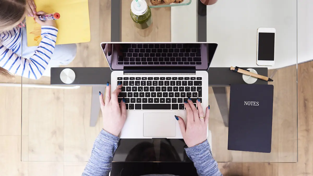 Woman typing on laptop at glass table while little girl drawing picture beside, top view model released Symbolfoto property released PUBLICATIONxINxGERxSUIxAUTxHUNxONLY IGGF00012