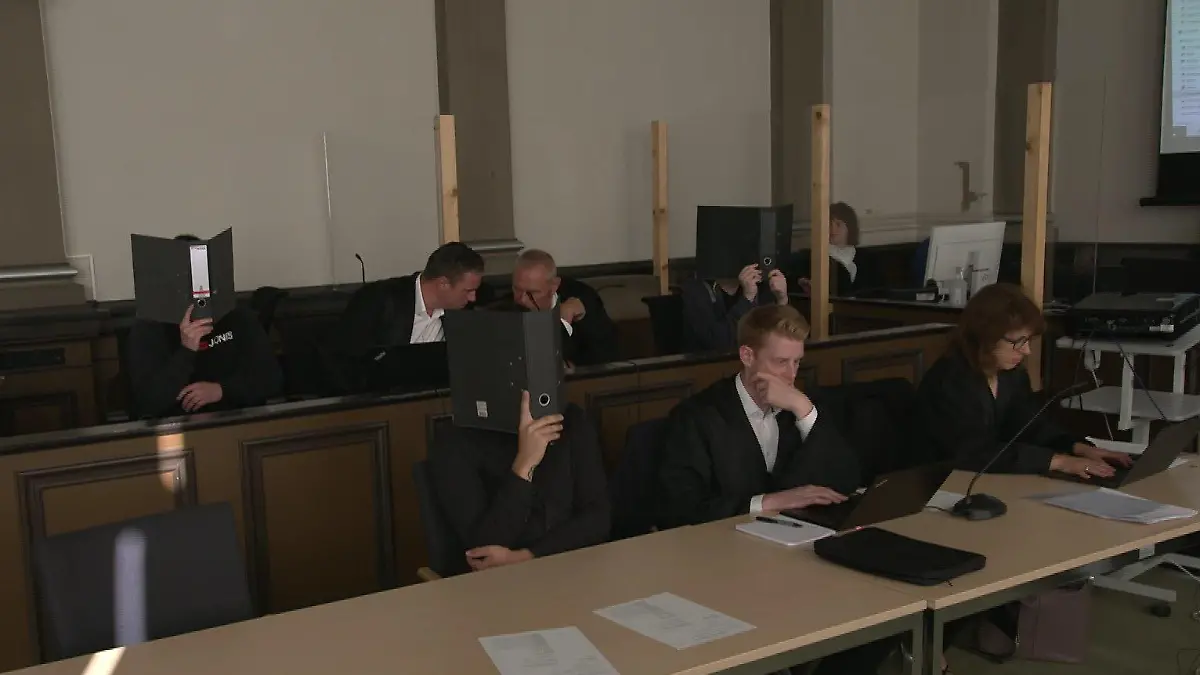 Die Angeklagten, 22, 24 und 26 Jahre alt, verdecken ihre Gesichter beim Prozessauftakt vor dem Landgericht Verden.