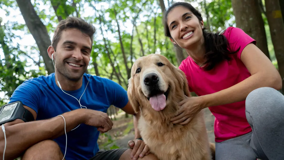 Portrait of a happy couple running with their dog at the park and smiling â healthy lifestyle concepts