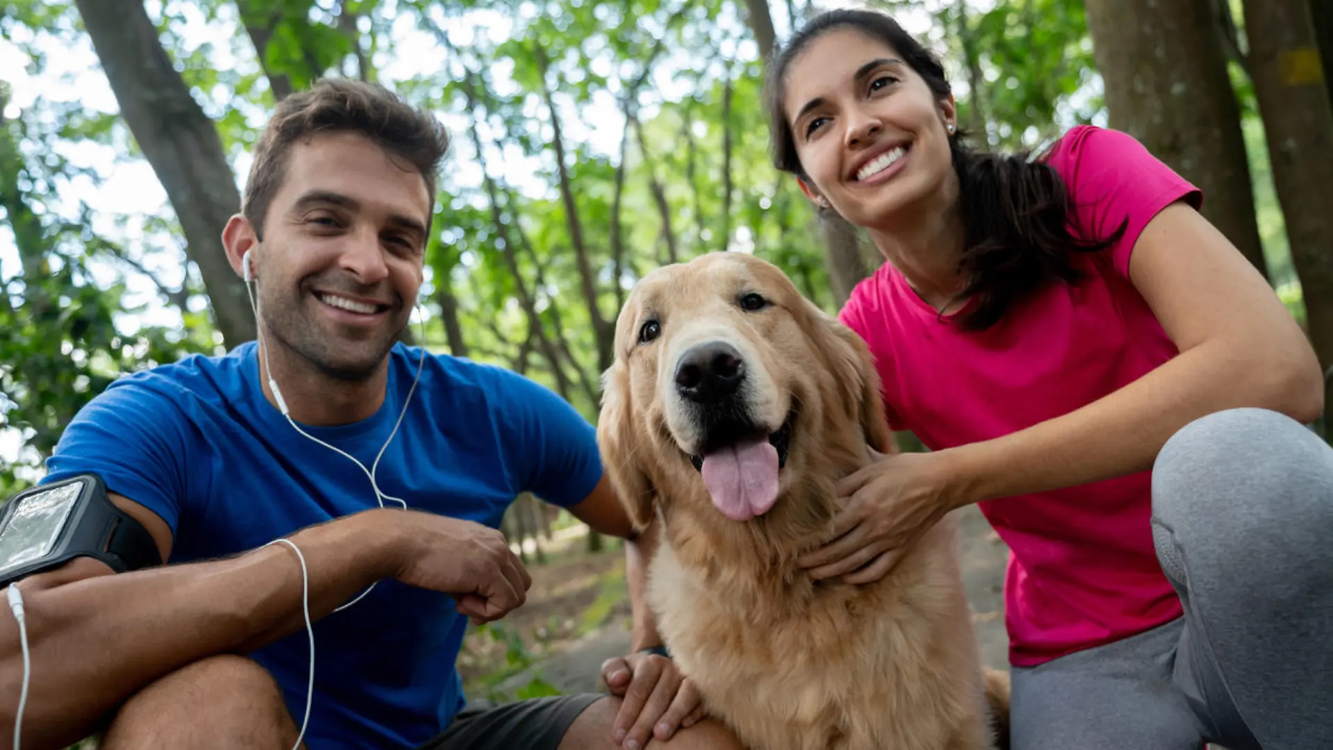 Portrait of a happy couple running with their dog at the park and smiling â healthy lifestyle concepts