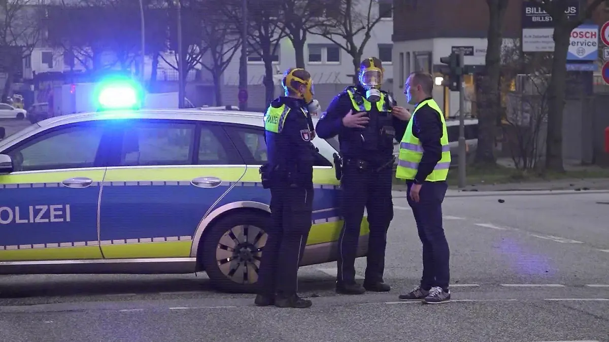 09.04.2023: Polizeieinsatzkräfte mit Schutzmasken nach einem Großbrand zweier Lagerhallen in Hamburg-Rothenburgsort