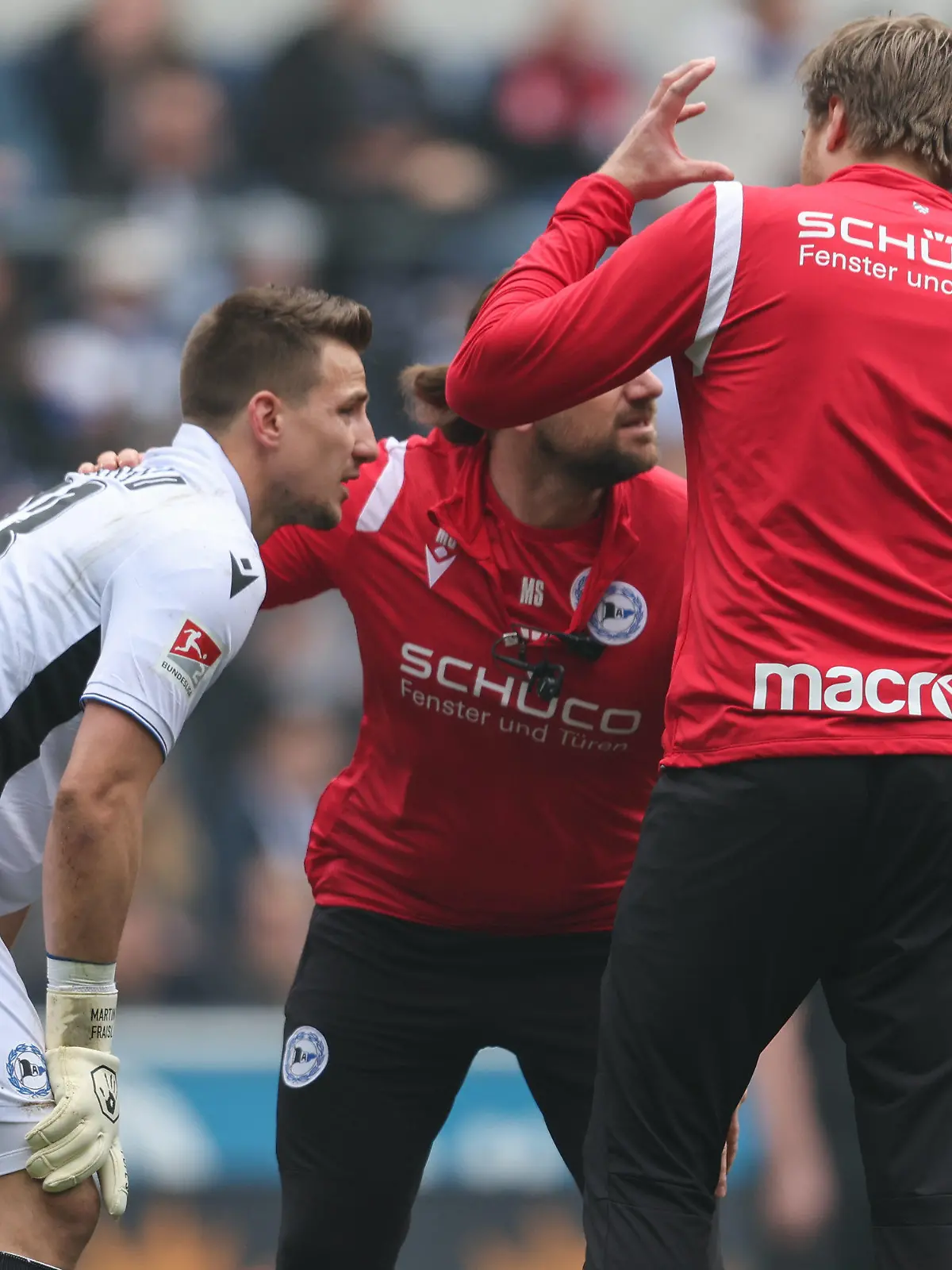 09.04.2023, Nordrhein-Westfalen, Bielefeld: Fußball: 2. Bundesliga, Arminia Bielefeld - Fortuna Düsseldorf, 27. Spieltag in der Schüco-Arena. Fans von Düsseldorf haben einen lauten Böller gezündet. Bielefelds Torwart Martin Fraisl (l) wird darauf hin behandelt. Foto: Friso Gentsch/dpa - WICHTIGER HINWEIS: Gemäß den Vorgaben der DFL Deutsche Fußball Liga bzw. des DFB Deutscher Fußball-Bund ist es untersagt, in dem Stadion und/oder vom Spiel angefertigte Fotoaufnahmen in Form von Sequenzbildern und/oder videoähnlichen Fotostrecken zu verwerten bzw. verwerten zu lassen. +++ dpa-Bildfunk +++