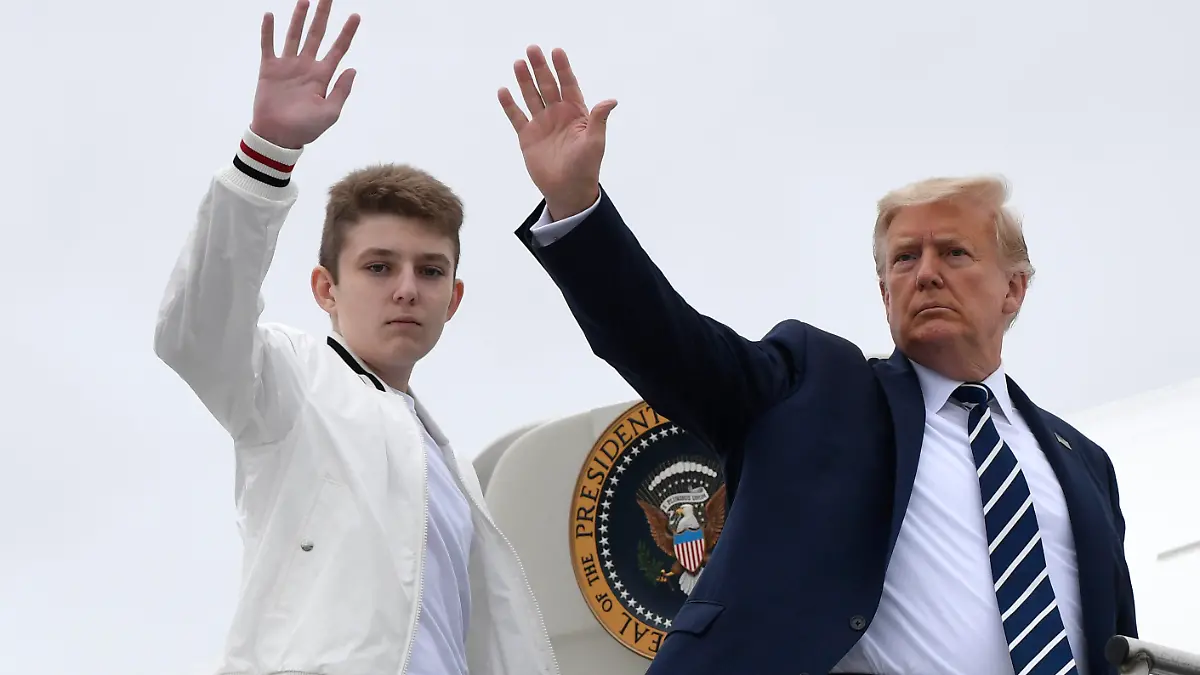 FILE - In this Aug. 16, 2020 file photo, President Donald Trump, right, and his son Barron Trump wave from the top of the steps to Air Force One at Morristown Municipal Airport in Morristown, N.J. (AP Photo/Susan Walsh)