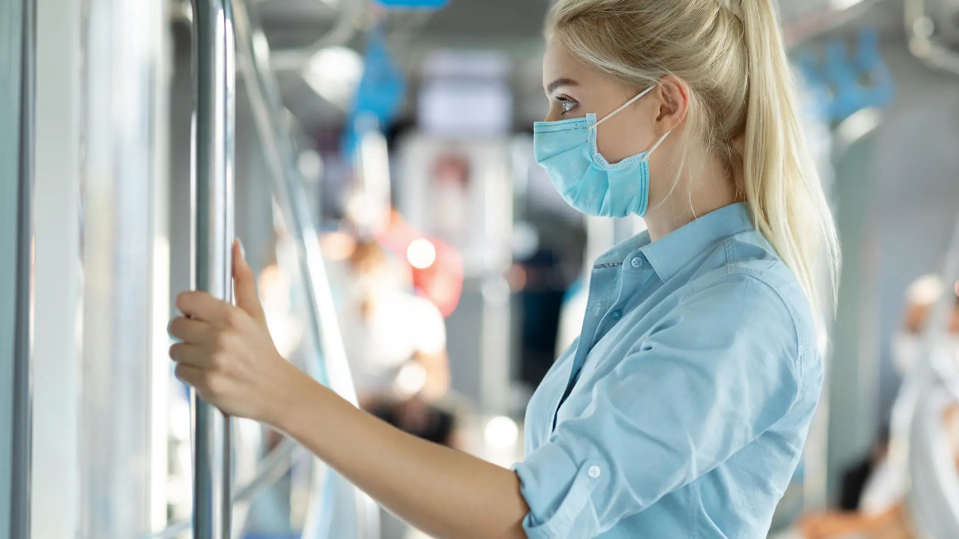 Frau fasst Stange in der Bahn an