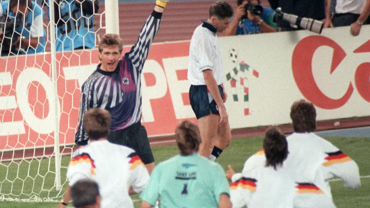Der deutsche Torhüter Bodo Illgner (l, oben) reisst triumphierend einen Arm hoch, und seine Mitspieler stürmen jubelnd auf ihn zu, während der englische Mittelfeldspieler Chris Waddle (M, hinten) nach dem verschossenen entscheidenden Elfmeter fassungslos ist. Die deutsche Fußballnationalmannschaft gewinnt am 04.07.1990 im Turiner Stadion delle Alpi das Halbfinalspiel der Fußball-WM gegen England mit 4:3 im Elfmeterschießen. Nach der Verlängerung hatte es 1:1 gestanden.
